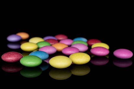 Lot of whole small sweet colourful candy isolated on black glassの写真素材