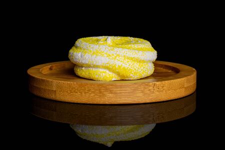 One whole yellow sweet meringue on bamboo coaster isolated on black glassの写真素材