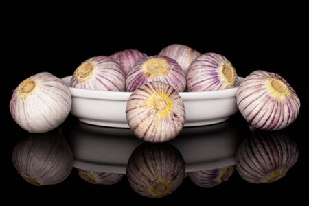 Lot of whole fresh purple single clove garlic in white oval ceramic bowl isolated on black glassの写真素材