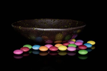 Lot of whole sweet colourful candy in glazed bowl isolated on black glassの写真素材