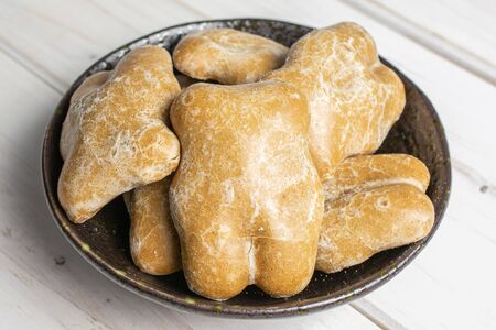 Lot of whole sweet brown gingerbread in dark ceramic bowl on white wood