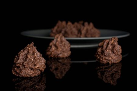 Group of seven whole homemade brown coconut cocoa biscuit on gray ceramic plate isolated on black glassの写真素材