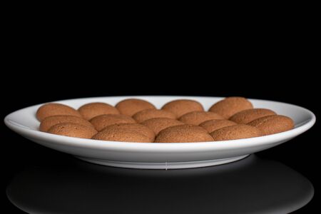 Lot of whole sweet brown chocolate sponge biscuit on white ceramic plate isolated on black glassの写真素材