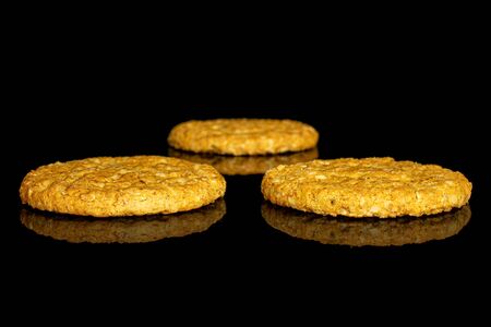 Group of three whole sweet golden oat cookie isolated on black glassの写真素材
