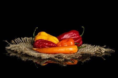 Group of five whole hot chili pepper on natural sackcloth isolated on black glassの写真素材
