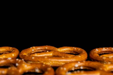 Lot of whole salty brown pretzel macro isolated on black glassの写真素材