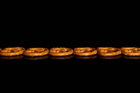 Group of six whole salty brown pretzel isolated on black glassの写真素材