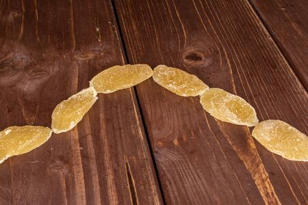 Group of six slices of dried yellow pineapple on brown wood