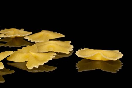 Group of six whole yellow pasta farfalle isolated on black glassの写真素材
