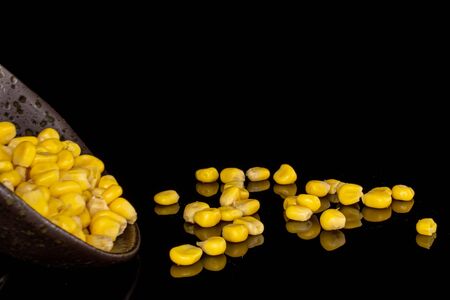 Lot of pieces of canned yellow corn in glazed bowl isolated on black glass