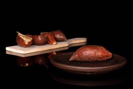 Group of three whole two halves of exotic brown salak on wooden cutting board with brown ceramic...