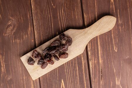 Lot of whole dried dark raisin on wooden cutting board flatlay on brown woodの写真素材
