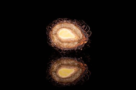One half of old brown rambutan isolated on black glassの写真素材