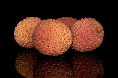 Group of four whole fresh lychee fruit isolated on black glassの写真素材