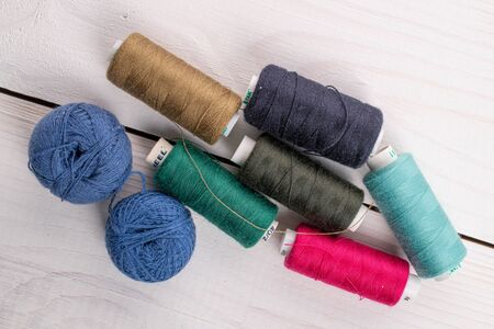 Lot of whole colourful thread spools on white wood
