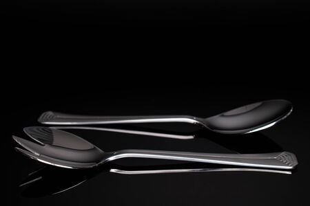 Group of two whole steel silver spoon isolated on black glassの写真素材