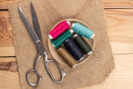 Scissors with thread spools on linen on wood