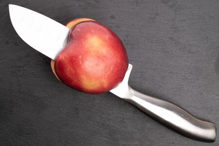 One sliced red delicious apple with knife on grey stoneの写真素材