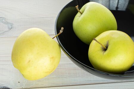 Group of three whole green delicious apple in bowl on white woodの写真素材