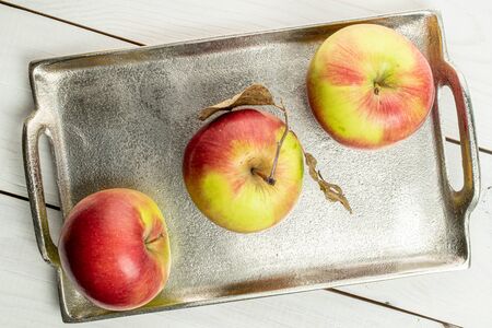 Group of three whole fresh garden apple on tray on white woodの写真素材