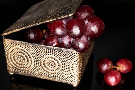Lot of whole fresh red globe grape in casket isolated on black glassの写真素材