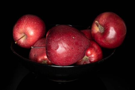 Group of five whole red delicious apple in dark bowl isolated on black glassの写真素材