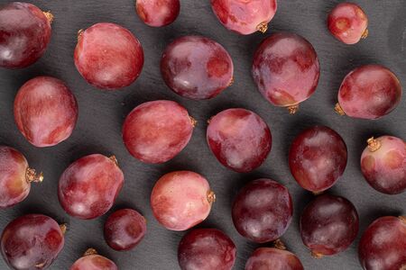 Lot of whole fresh red globe grape berries on grey stoneの写真素材