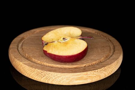 One half of red delicious apple on wooden plate isolated on black glass