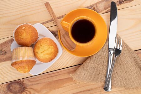 Group of three whole small baked muffin with coffee for breakfast on wood