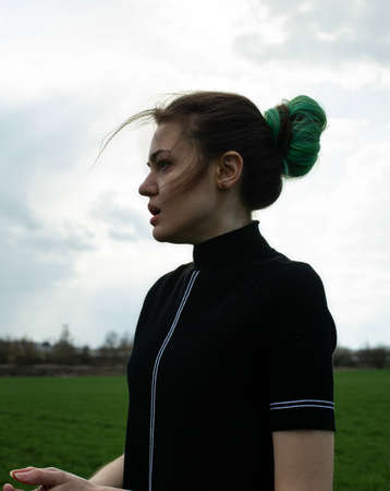 Emotional portrait of white girl on green field with sky behindの写真素材