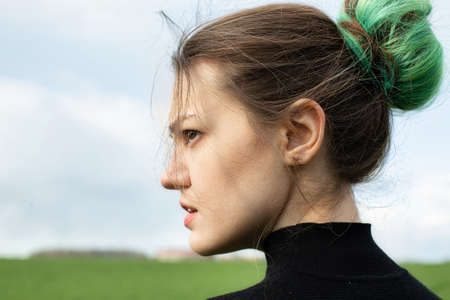 Emotional portrait of girl in black on green field with sky behindの写真素材