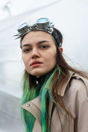 Serious girl with green hair glasses on head on whiteの写真素材