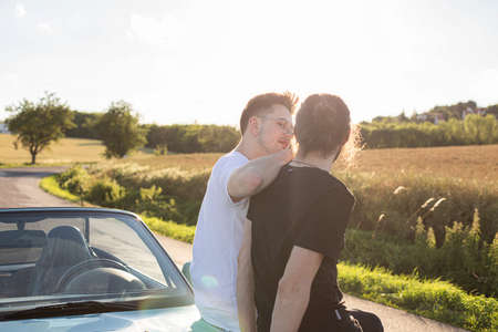 White european boys outside sitting on the hood of carの写真素材