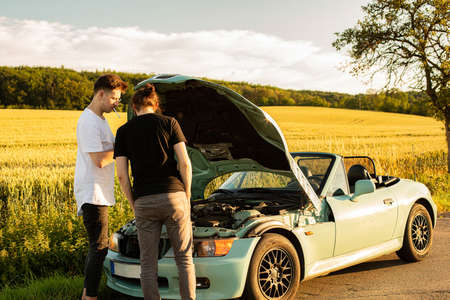 White european boys outside looking under the hood of a car