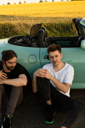White young european models boys outside sitting on the road near carの写真素材