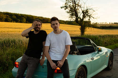 Young white european models boys outside sitting on the car