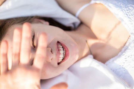 White young girl model with hand near the face smiling on whiteの写真素材