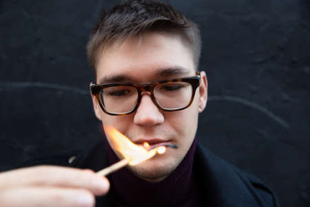 European young white man with a match close-up portrait isolated on blackの写真素材