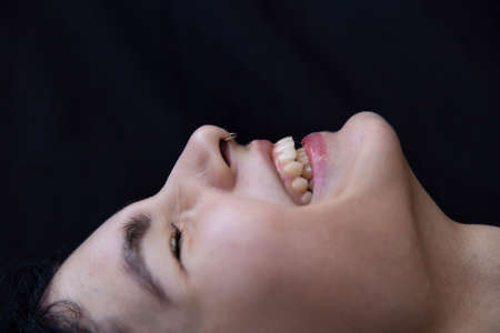 Laughing white young woman close-up portrait isolated on blackの写真素材