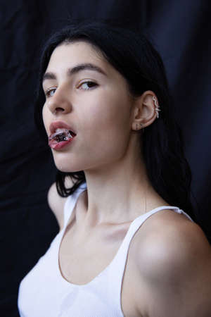 Woman with dark hair isolated on black with ice in her lipsの写真素材