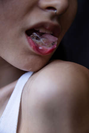 Halves quarters slices of european white girl close-up portrait isolated on black with an ice in her mouthの写真素材