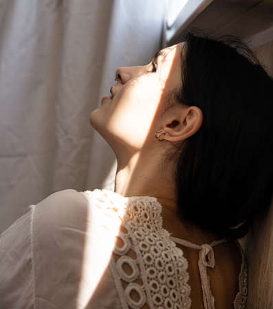 White girl with dark hair on white in shadowの写真素材