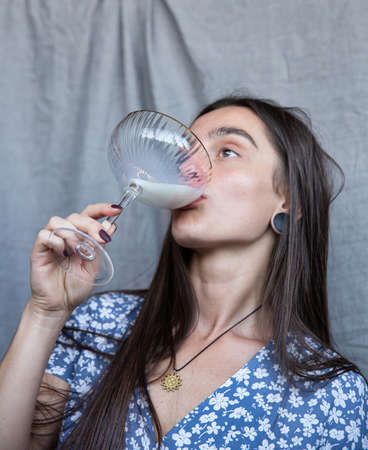 White young woman isolated on dark grey drinking