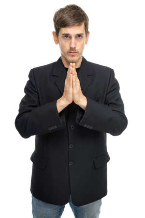 Young handsome tall slim white man with brown hair with clasped hands in black blazer in blue jeans isolated on white backgroundの写真素材