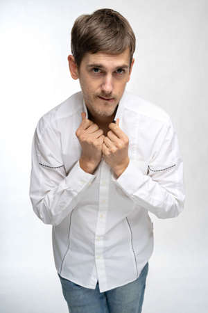 Young handsome tall slim white man with brown hair looks kinky in white shirt isolated on white...