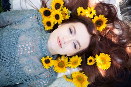 White young girl with dark hair and blue eyes lying portrait within sunflowersの写真素材