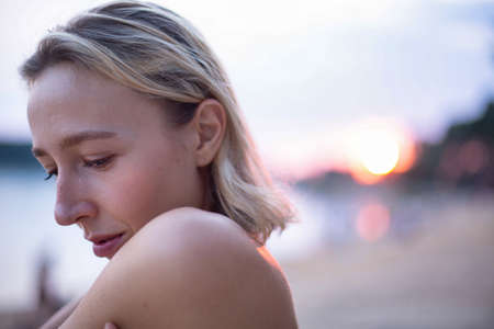 Portrait young white european woman with lake behind in sunsetの写真素材