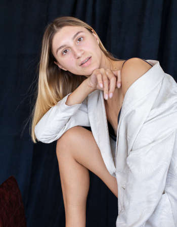 Young white girl with blonde hair in white clothes isolated on blackの写真素材