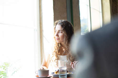 European girl with dark hair with window behind in cafeの写真素材