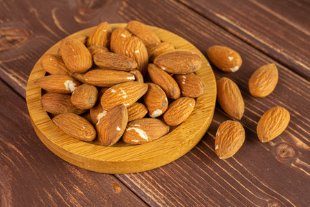 Lot of whole almond on bamboo coaster on brown woodの写真素材